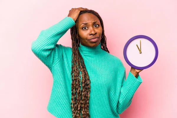 Pembe Arka Planda Bir Saat Tutan Genç Afrikalı Amerikalı Kadın — Stok fotoğraf