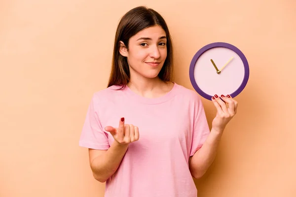 Joven Mujer Hispana Sosteniendo Reloj Aislado Sobre Fondo Beige Señalándote — Foto de Stock