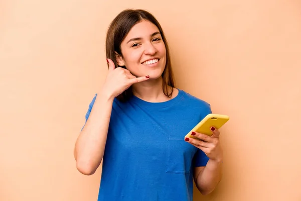Mladá Běloška Drží Mobilní Telefon Izolovaný Béžovém Pozadí Ukazující Gesto — Stock fotografie