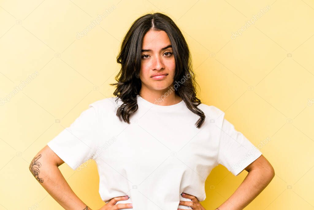 Young hispanic woman isolated on yellow background sad, serious face, feeling miserable and displeased.