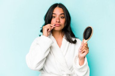 Mavi arka planda saç fırçası tutan genç İspanyol kadın dudaklarında parmaklarıyla bir sır saklıyor..