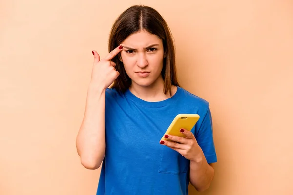 휴대폰을 코카서스 여성은 손가락으로 스러운 몸짓을 베이지 배경에서 고립되어 — 스톡 사진