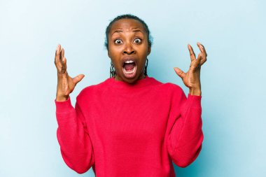 Genç Afrikalı Amerikalı kadın mavi arka planda izole edilmiş gökyüzüne haykırıyor, yukarı bakıyor, hayal kırıklığına uğramış..