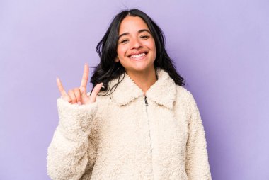 Mor arka planda izole edilmiş genç İspanyol kadın boynuzlarını devrim konsepti olarak gösteriyor..