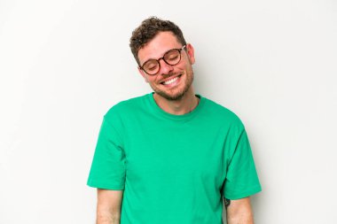 Beyaz arka planda izole edilmiş genç beyaz adam gülüyor ve gözlerini kapıyor, rahatlamış ve mutlu hissediyor..