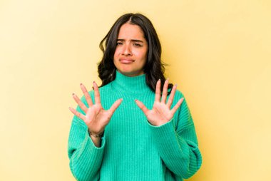 Sarı arka planda izole edilmiş genç İspanyol kadın tiksinti belirtisi gösteren birini reddediyor..