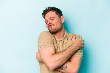 Kafkasyalı genç adam mavi arka planda izole edilmiş, güler yüzlü ve mutlu..