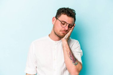 Mavi arka planda izole edilmiş, sıkılmış, yorgun ve dinlenmeye ihtiyacı olan genç beyaz bir adam..