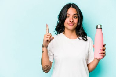 Mavi arka planda termometreyi tutan genç İspanyol kadın bir numarayı parmağıyla gösteriyor..