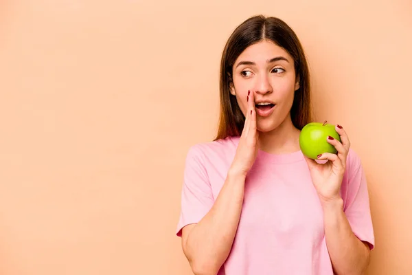 Young Hispanic Woman Holding Apple Isolated Beige Background Saying Secret — Stock Photo, Image
