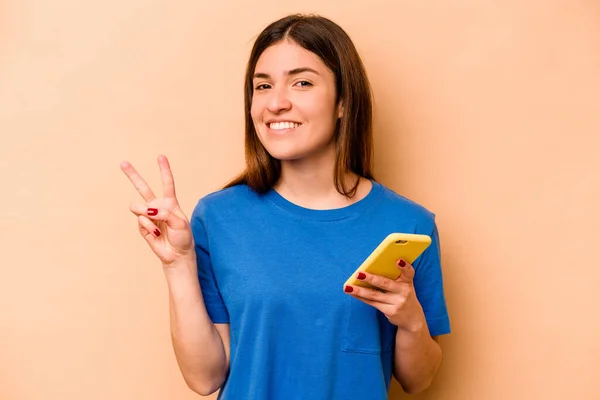 Młoda Kaukaska Kobieta Trzyma Telefon Komórkowy Odizolowany Beżowym Tle Pokazuje — Zdjęcie stockowe