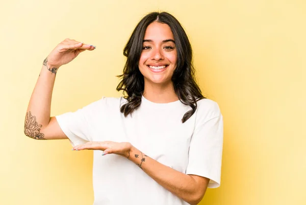 Young Hispanic Woman Isolated Yellow Background Holding Something Little Forefingers — Fotografie, imagine de stoc