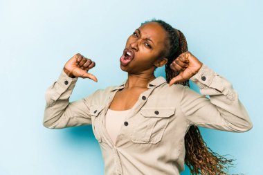 Mavi arka planda izole edilmiş genç Afrikalı Amerikalı kadın gururlu ve kendinden emin hissediyor, örnek olarak.