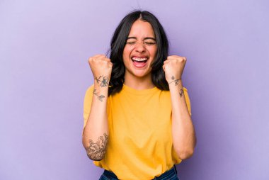 Mor arka planda izole edilmiş genç İspanyol kadın tasasız ve heyecanlı bir şekilde tezahürat yapıyor. Zafer konsepti.