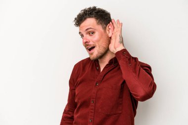 Beyaz arka planda izole edilmiş genç beyaz adam bir dedikoduyu dinlemeye çalışıyor..