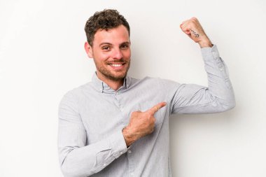 Beyaz arka planda izole edilmiş genç beyaz bir adam güçlü bir hareket gösteriyor, kollarıyla, kadınsı gücün sembolü.