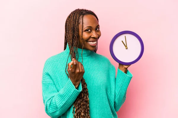Молодая Афроамериканка Держит Часы Изолированные Розовом Фоне Указывая Пальцем Тебя — стоковое фото