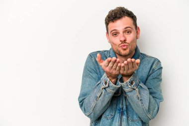 Beyaz arka planda izole edilmiş genç beyaz bir adam dudaklarını katlıyor ve hava öpücüğü vermek için avuç içleri tutuyor..