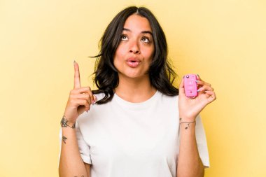 Pembe arka planda izole edilmiş anahtar taşıyan İspanyol kadın ağzı açık bir şekilde üst tarafı işaret ediyor..