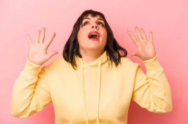 Pembe arka planda izole edilmiş genç beyaz kadın gökyüzüne haykırıyor, yukarı bakıyor, hayal kırıklığına uğramış..