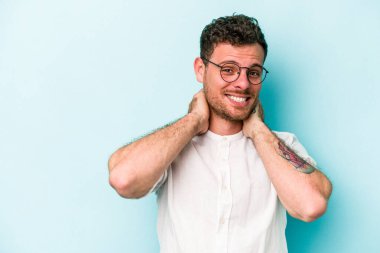 Kafkasyalı genç adam mavi arka planda izole edilmiş kafasının arkasına dokunuyor, düşünüyor ve bir seçim yapıyor..