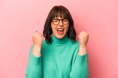 Pembe arka planda soyutlanmış, tasasız ve heyecanlı genç bir beyaz kadın. Zafer konsepti.