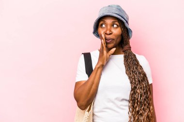 Pembe arka planda izole edilmiş plaja giden genç Afrikalı Amerikalı kadın gizli bir sıcak fren haberi veriyor ve kenara bakıyor.