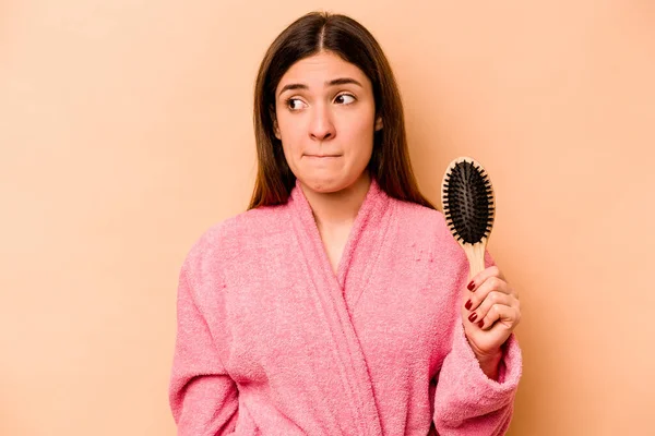 Bej Arka Planda Saç Fırçası Tutan Genç Spanyol Kadın Şaşkın — Stok fotoğraf