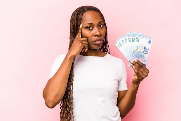 Mladá Afroameričanka Držící Bankovky Izolované Růžovém Pozadí Ukazující Prstem Chrám — Stock fotografie