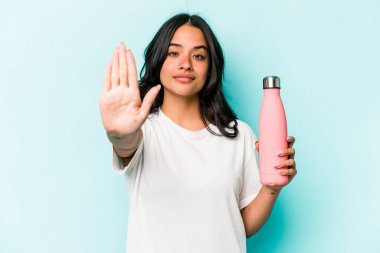 Mavi arka planda termometreyi tutan genç İspanyol kadın elini uzatmış, dur işareti veriyor ve seni engelliyor..