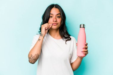 Mavi arka planda termosu olan genç İspanyol kadın dudaklarında parmaklarıyla bir sır saklıyor..