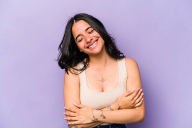 Mor arka planda izole edilmiş genç İspanyol kadın gülüyor ve eğleniyor..