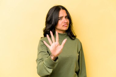 Sarı arka planda izole edilmiş genç İspanyol kadın tiksinti belirtisi gösteren birini reddediyor..