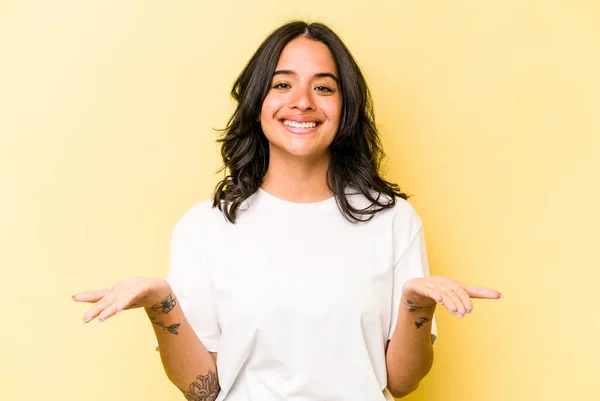 Young Hispanic Woman Isolated Yellow Background Makes Scale Arms Feels — Stock Photo, Image