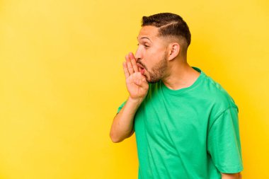 Sarı arka planda izole edilmiş genç İspanyol bir adam gizli bir sıcak fren haberi veriyor ve yana bakıyor.