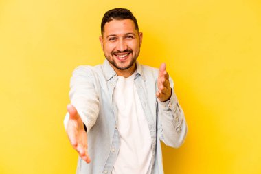 Sarı arka planda izole edilmiş genç İspanyol adam kameraya sarıldığı için kendinden emin hissediyor..