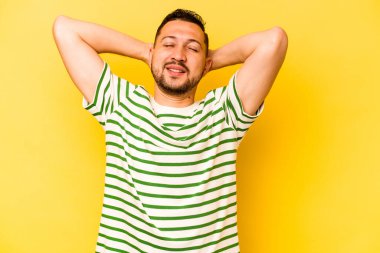 Sarı arka planda izole edilmiş genç bir İspanyol. Kollarını uzatıyor, rahat duruyor..