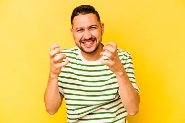 Sarı arka planda izole edilmiş genç İspanyol adam gergin elleriyle çığlık atıyor..