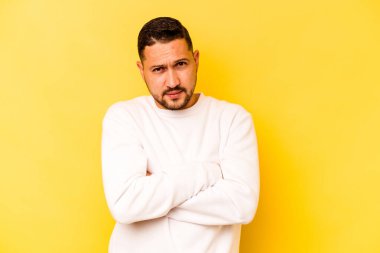 Sarı arka planda izole edilmiş genç bir İspanyol şüpheli, belirsiz, seni muayene ediyor..