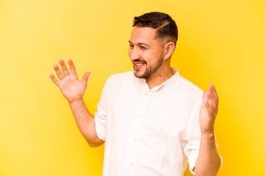 Genç İspanyol adam sarı arka planda izole edilmiş neşeli bir şekilde gülüyor. Mutluluk kavramı.