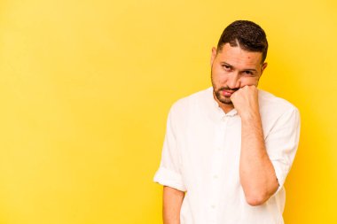 Sarı arka planda izole edilmiş, üzgün ve dalgın hisseden genç bir İspanyol fotokopi odasına bakıyor..