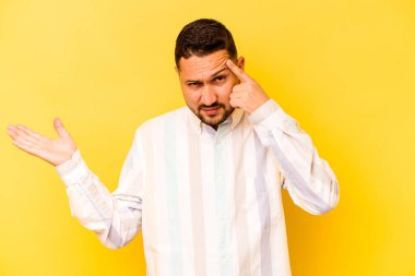 Sarı arka planda izole edilmiş genç İspanyol adam işaret parmağıyla bir hayal kırıklığı gösteriyor..
