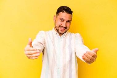 Sarı arka planda izole edilmiş genç bir İspanyol hoş geldin ifadesi sergiliyor..