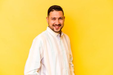 İspanyol asıllı genç adam sarı arka planda izole edilmiş. Kendine güveniyor. Kalçaları tutuyor..