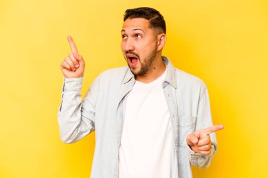 Sarı arka planda izole edilmiş genç İspanyol adam farklı kopya alanlarını gösteriyor, birini seçiyor, parmaklarıyla gösteriyor.
