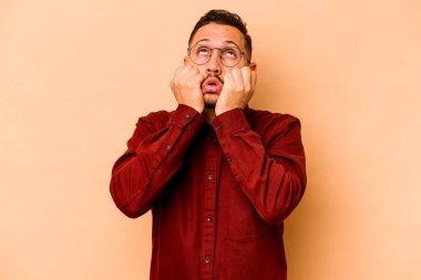 Latin kökenli genç bir adam bej arka planda izole edilmiş ağlıyordu, bir şeyden mutsuzdu, ıstırap ve kafa karışıklığı vardı..