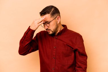 Latin kökenli genç bir adam bej arka planda izole edilmiş, başı ağrıyor, yüzüne dokunuyor..