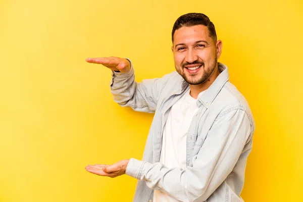 Jovem Hispânico Isolado Fundo Amarelo Segurando Algo Pouco Com Dedos — Fotografia de Stock