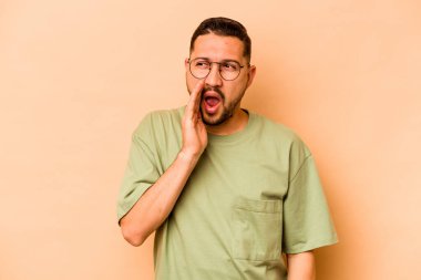 Latin kökenli genç adam bej arka planda izole edilmiş..