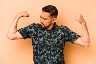 Latin kökenli genç bir adam bej arka planda izole edilmiş. Güçlü hareketler sergiliyor. Kadın gücünün sembolü.
